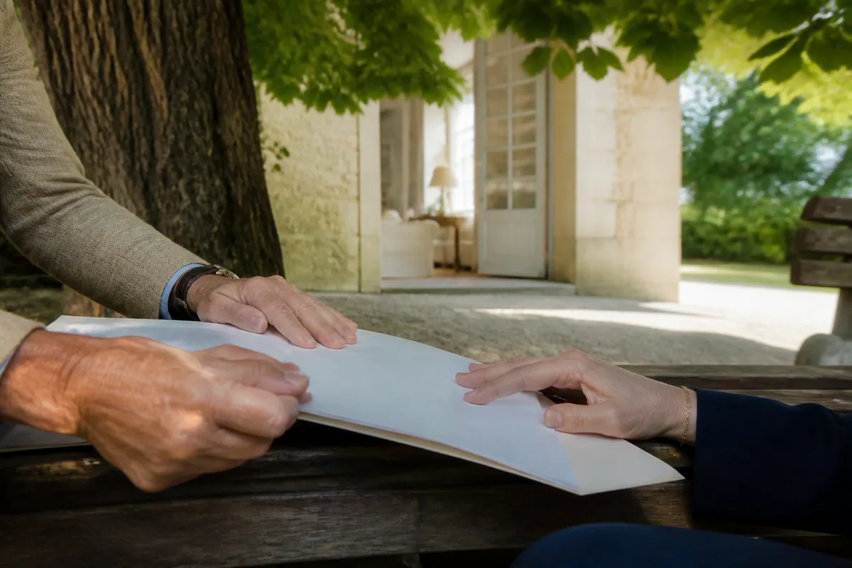 Deux mains posées sur un dossier ouvert, échange calme entre deux personnes